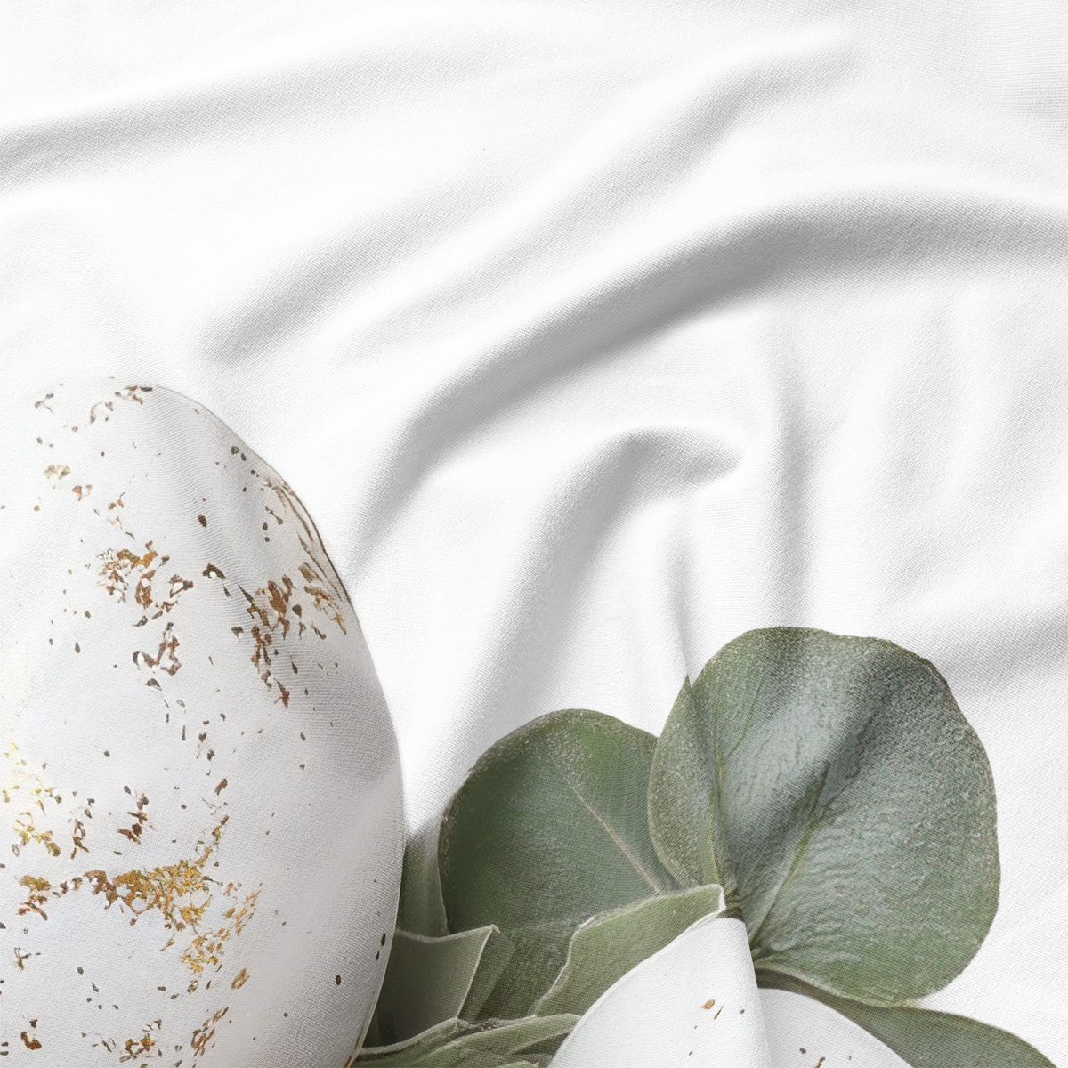 Detale nadruku: biały pisankowy motyw z subtelnymi złotymi akcentami i liśćmi eukaliptusa na tkaninie