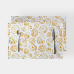 Podkładka z białym tłem i wzorem złotych pisanek, widok z góry z nożem i widelcem