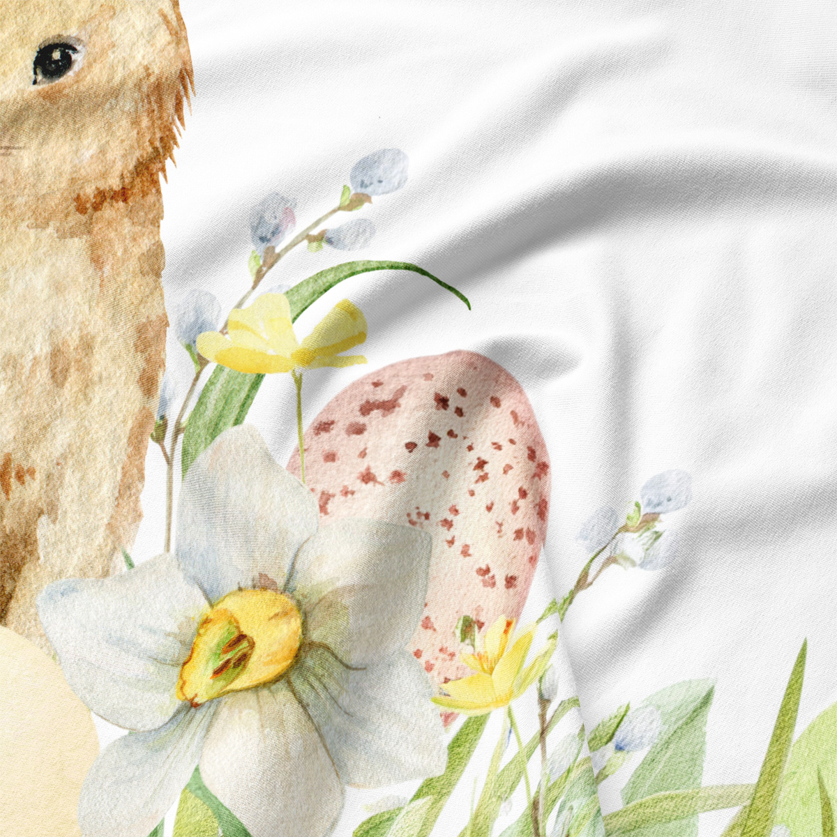 Zbliżenie na akwarelowy narcyz i nakrapianą pisankę na tkaninie