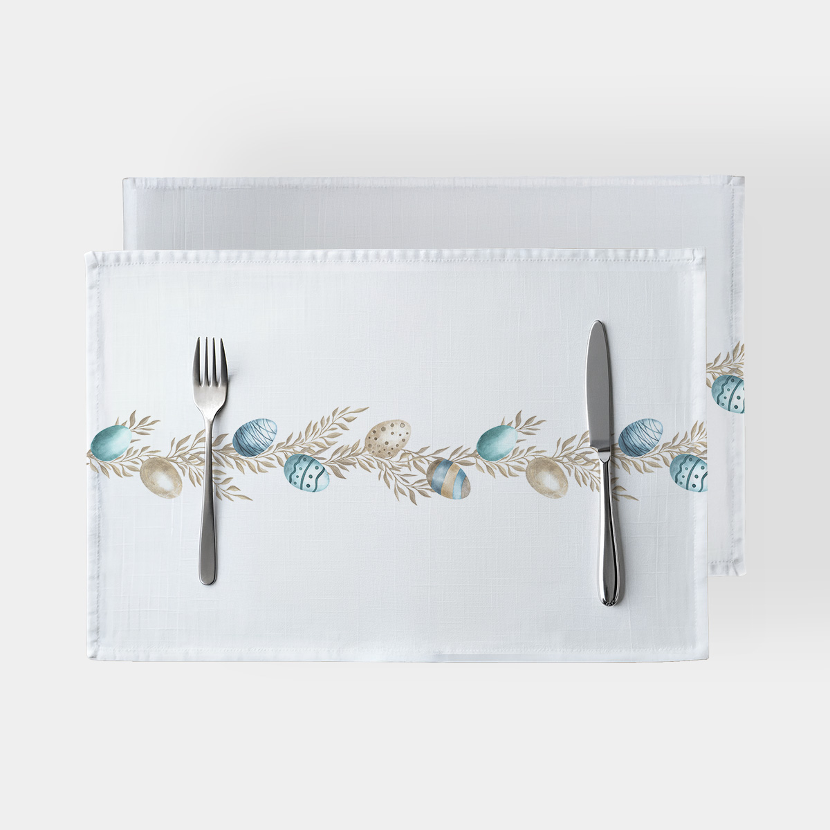 Białe podkładki z poziomym motywem gałązek i pastelowych pisanek na środku stołu