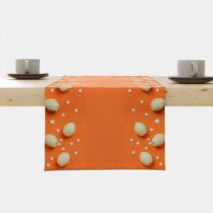 Pomarańczowy bieżnik rozłożony na stole z kremowymi pisankami i gwiazdkami