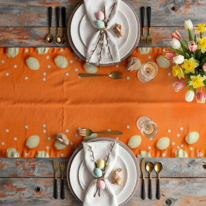 Aranżacja stołu ze świątecznymi talerzami, kwiatami i bieżnikiem w pomarańczowym kolorze