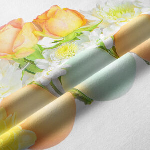 Zbliżenie tkaniny z nadrukiem pastelowych jajek oraz żółto-różowych kwiatów i zielonych liści