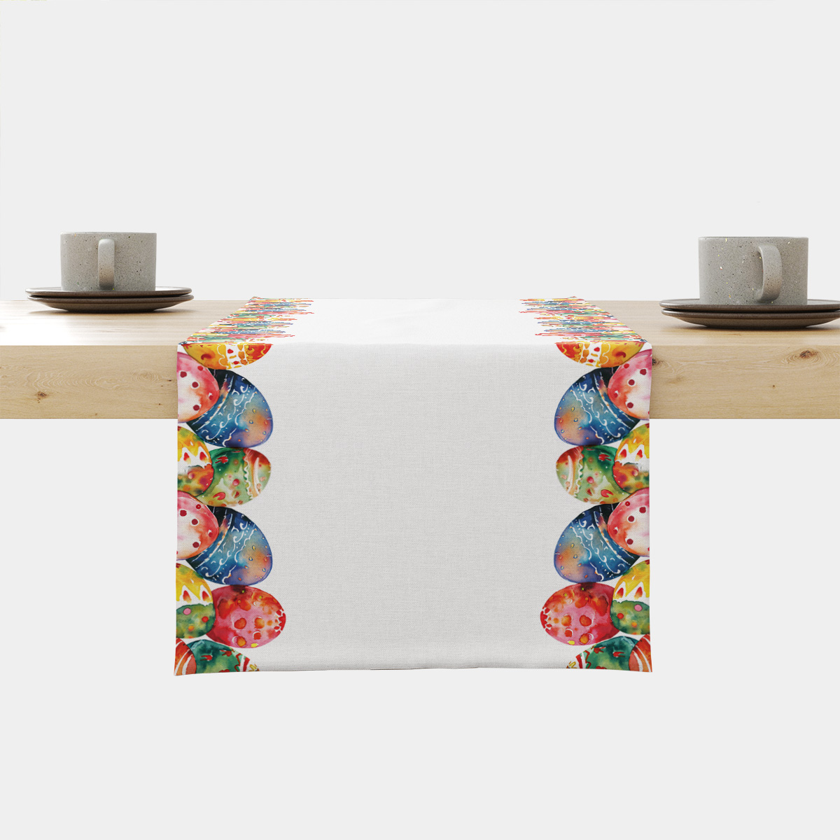 biały bieżnik z kolorowymi akwarelowymi pisankami ułożonymi przy krawędziach na drewnianym stole