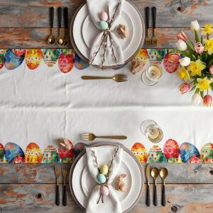 aranżacja stołu z białą zastawą, bukietem tulipanów i bieżnikiem ozdobionym pisankami przy krawędziach
