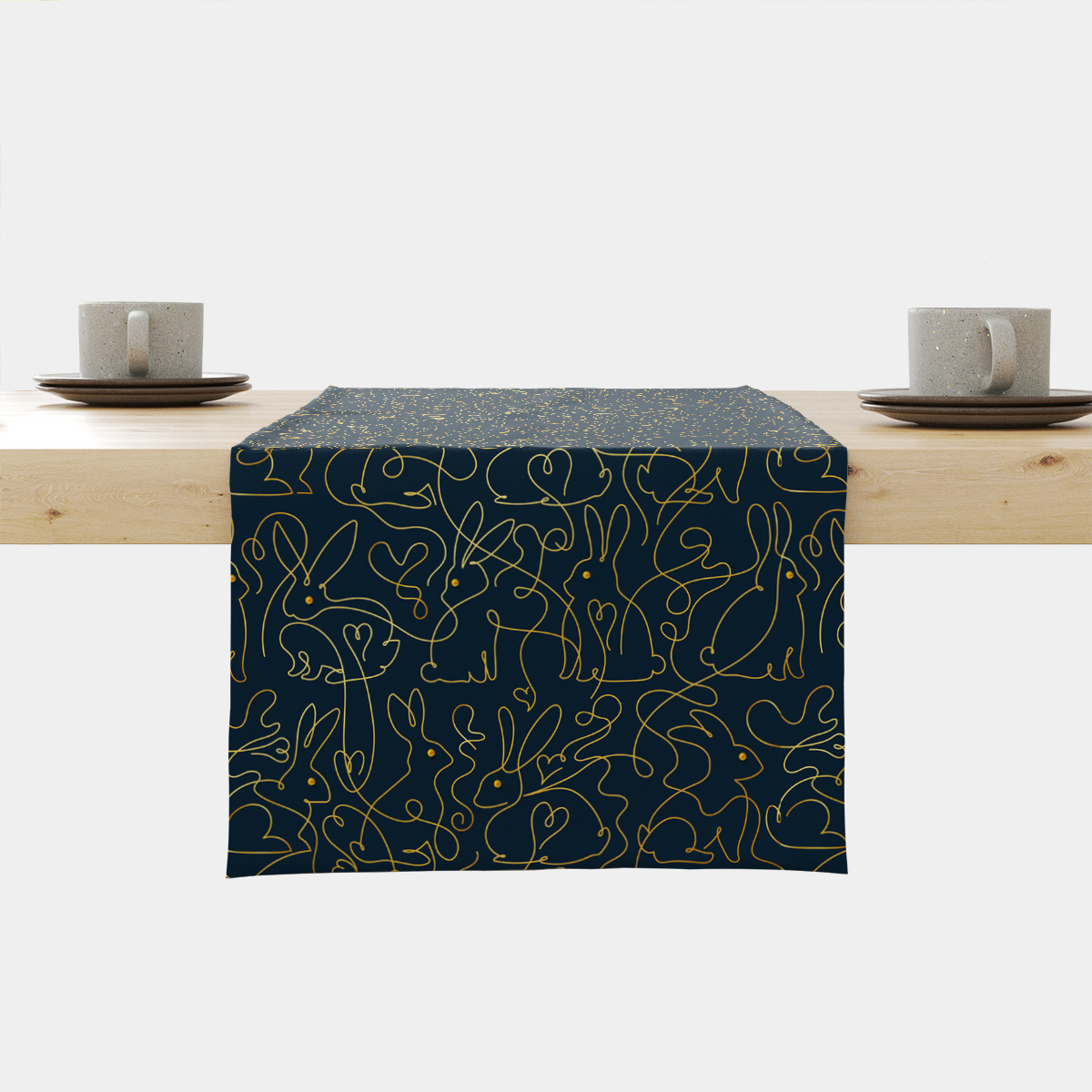 Bieżnik ułożony na stole z granatowym tłem i złotym wzorem z zajączków widok frontalny