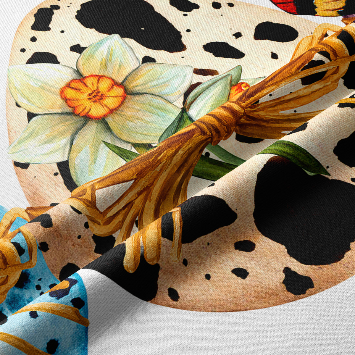 Zbliżenie na detal nadruku: pisanka z kwiatem i dekoracyjną wstążką wykonane techniką akwareli