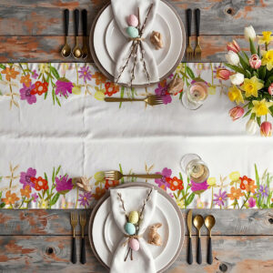 Widok z góry na nakryty stół z bieżnikiem, talerzami, pisankami i bukietem tulipanów w aranżacji wielkanocnej