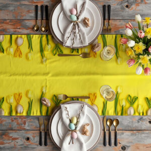 Widok z góry na świąteczne nakrycie stołu z bieżnikiem, talerzami, sztućcami i bukietem tulipanów