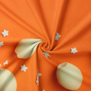 Zbliżenie na tkaninę pokazujące kremowy motyw pisanki i małe gwiazdki na pomarańczowym tle