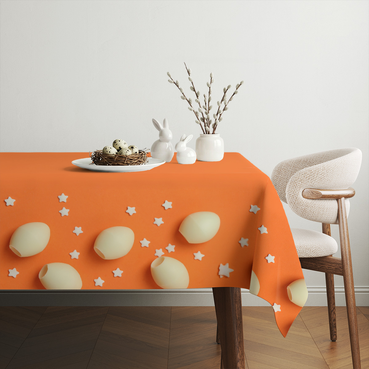 Aranżacja stołu z wiklinowym koszykiem, talerzem z jajkami i pomarańczowym obrusem