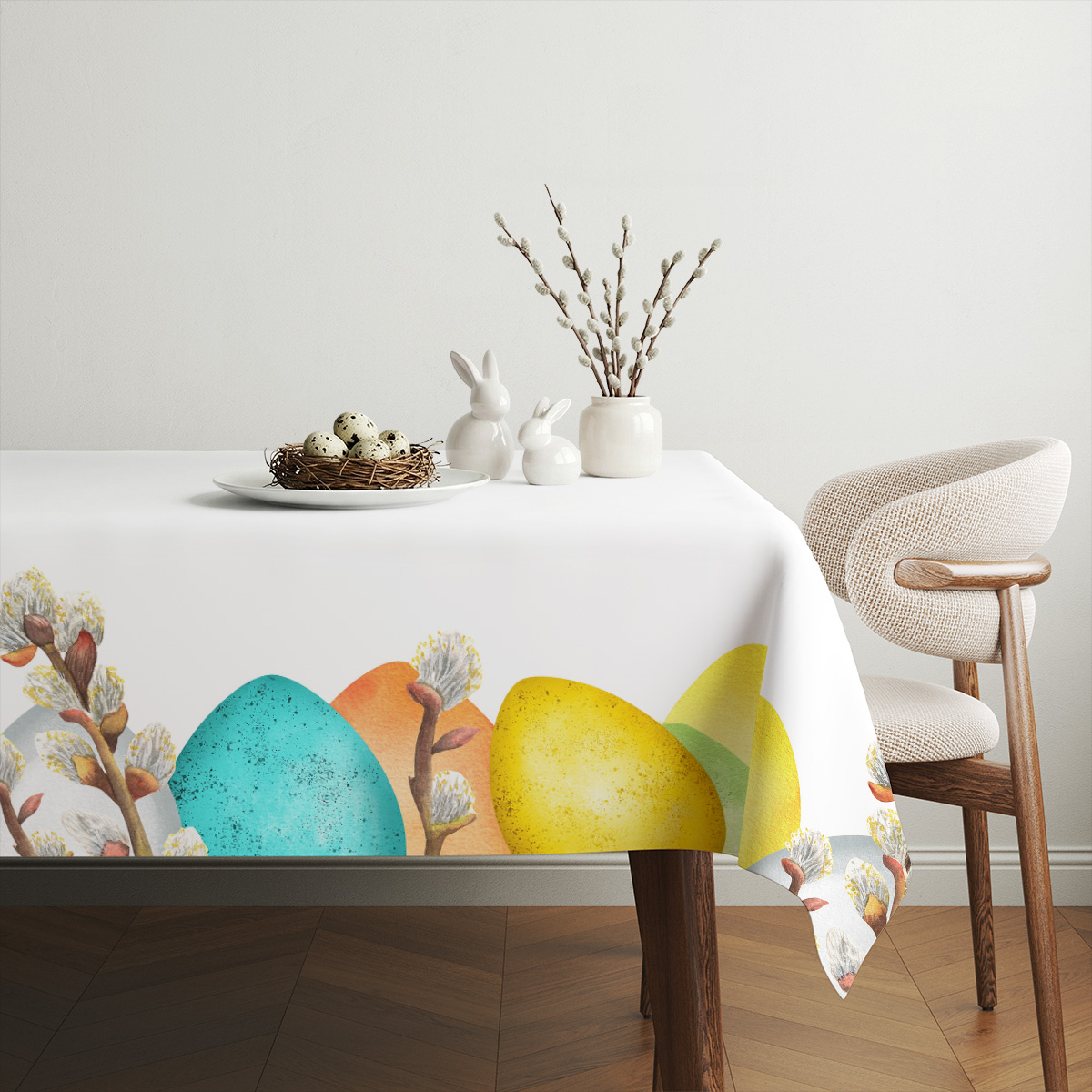 Aranżacja stołu z białą ceramiką, bukietem bazi i obrusem ozdobionym rytmicznym wzorem pisanek