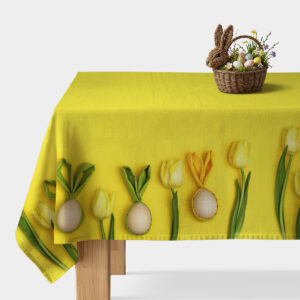 Główne ujęcie żółtego obrusa z motywem tulipanów i pisanek na brzegu stołu