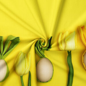 Zbliżenie na detal tkaniny z tulipanem i dekoracyjną pisanką oraz widoczną fakturą nadruku