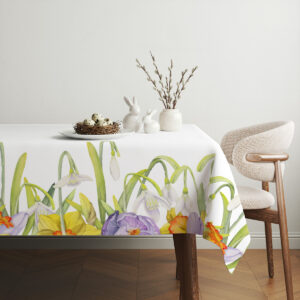 Aranżacyjne ujęcie stołu z koszykiem i dekoracjami obok obrusa z wiosennym wzorem