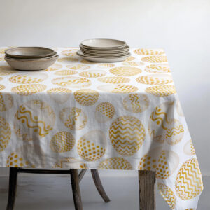 Stół nakryty obrusem z pisankami z ceramicznymi talerzami i miseczkami