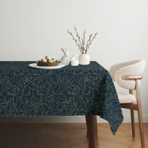 Aranżacja stołu z koszyczkiem i dekoracjami na obrusie z motywem złotych zajączków