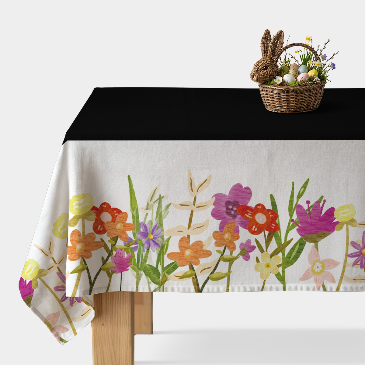 Obrus z czarnym środkiem i malowanym pasem łąkowych kwiatów przy brzegu stołu, aranżacja z koszykiem z pisankami