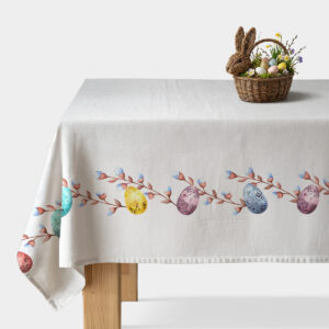 biały obrus z pasem akwarelowych pisanek i gałązek na stole z dekoracyjnym koszykiem