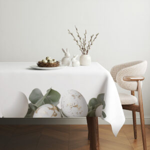 aranżacja stołu z obrusem, ceramiczne zające, gniazdo z jajkami i gałązki bazie w tle