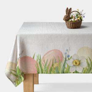 Obrus z motywem pastelowych pisanek i trawy rozłożony na stole z koszyczkiem z jajkami