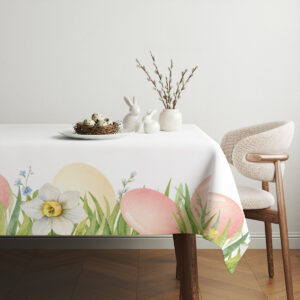Aranżacja stołu z obrusem w pastelowe jaja, ceramicznymi zajączkami i gałązkami kotków