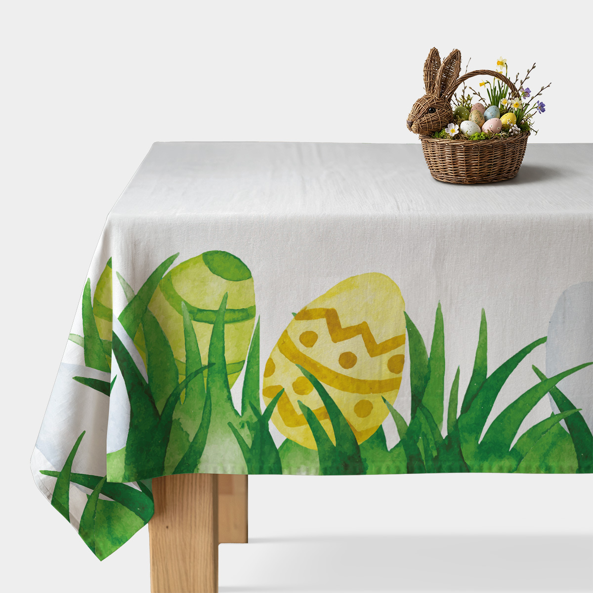 biały obrus z malowanymi żółto-zielonymi pisankami i trawą na stole, główne ujęcie produktu