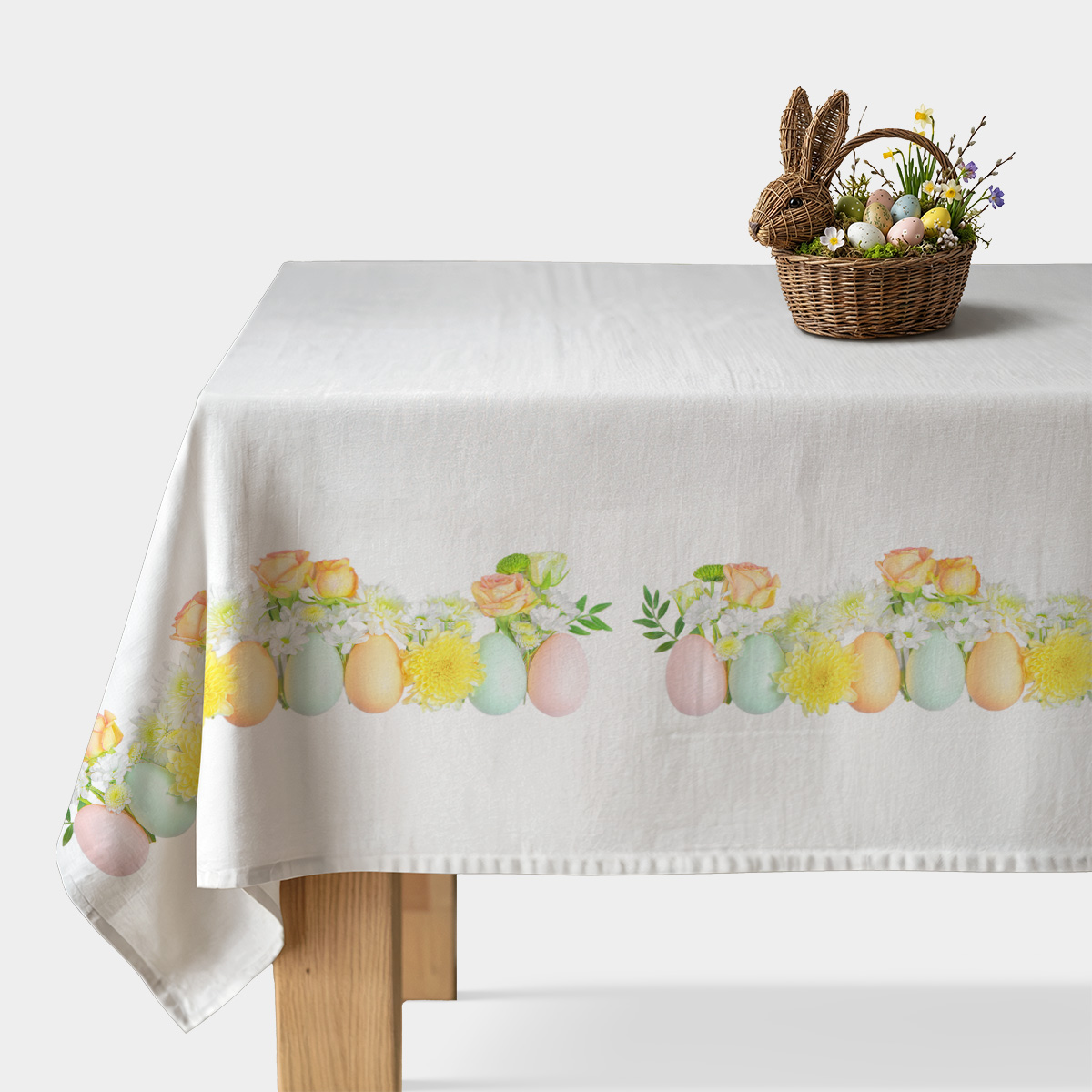 Obrus na jasnym stole z poziomym paskiem pastelowych jajek i żółtych kwiatów