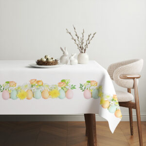 Aranżacja stołu z obrusem, wiklinowym koszykiem z pisankami i gałązkami bazi