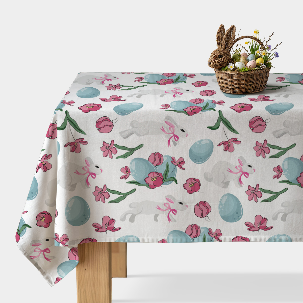 obrus na stole z koszykiem wielkanocnym, widok główny na biały obrus z niebieskimi pisankami i różowymi tulipanami