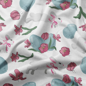 Zbliżenie na materiał z niebieskimi pisankami, różowymi tulipanami i subtelnym zającem wstążką