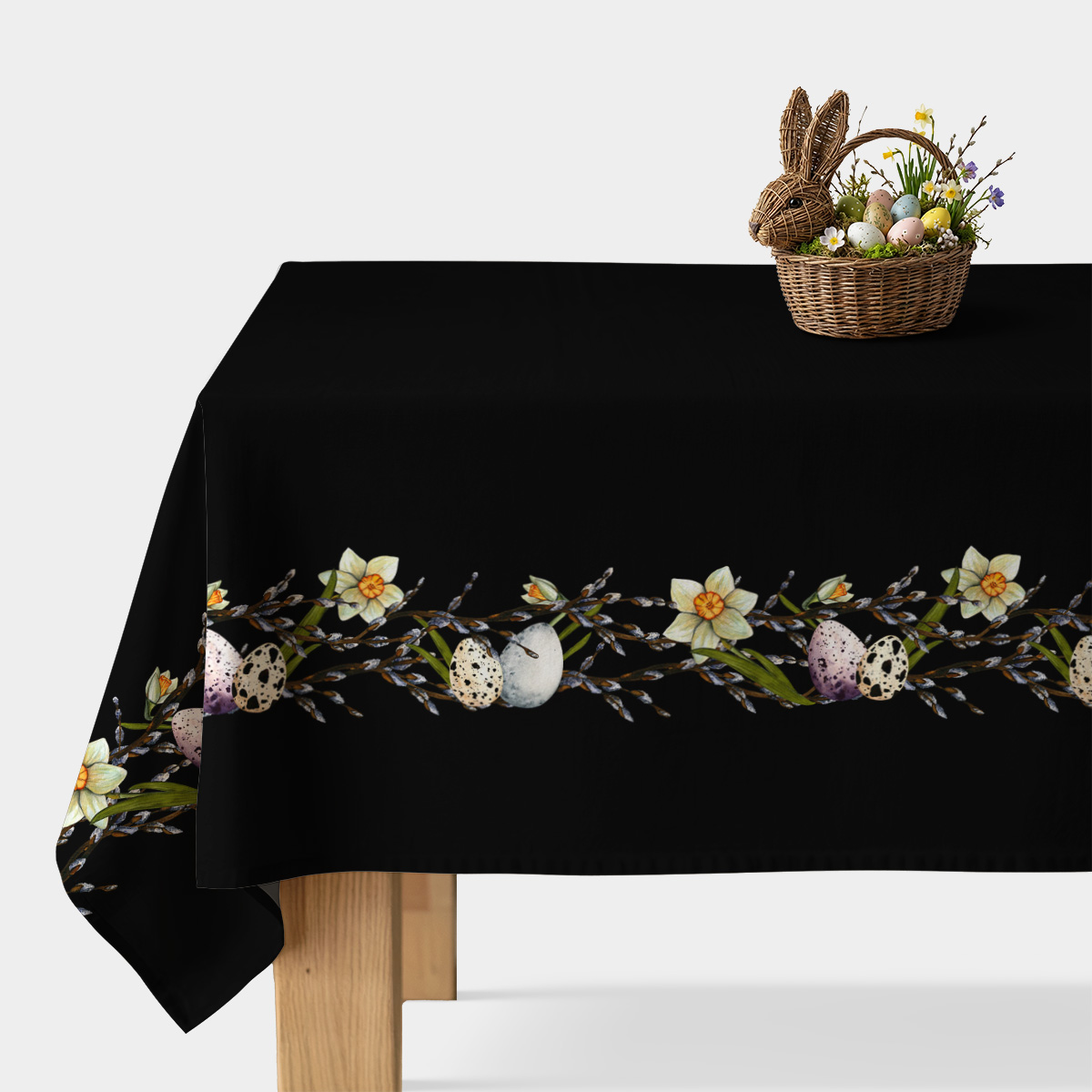 Czarny obrus z poziomym pasem żonkilów, baziówek i malowanych pisanek na stole