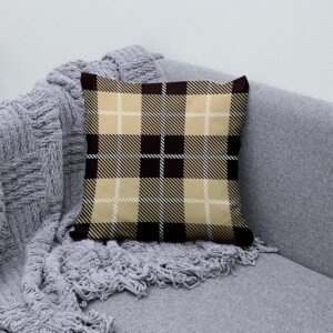 Aranżacja na sofie: poduszka ozdobna w kratę beż i brąz obok plecionego koca
