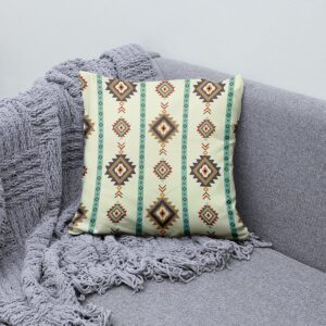 Poduszka ułożona na szarym fotelu obok plecionej narzuty, widoczne detale wzoru