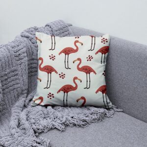 Poduszka ozdobna z flamingami ułożona na kanapie obok pledu