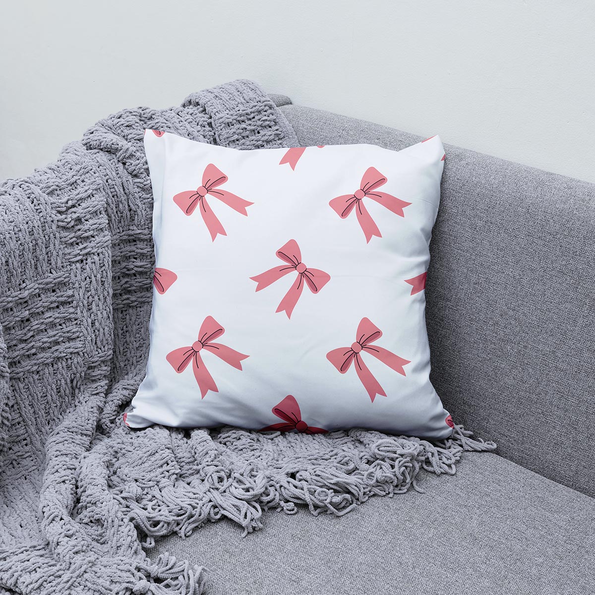 Poduszka ozdobna z kokardkami ułożona na kanapie jako element aranżacji