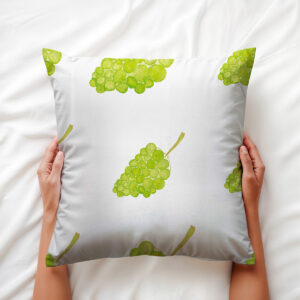 Ręce trzymające poduszkę z wzorem akwarelowych winogron, widoczny detal nadruku i faktura materiału