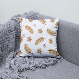 aranżacyjny kadr poduszki z motywem piór i kwiatów na szarej kanapie z plecionym kocem