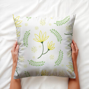 poduszka trzymana w dłoniach, widoczny detal żółtych kwiatów i łuków zielonych listków