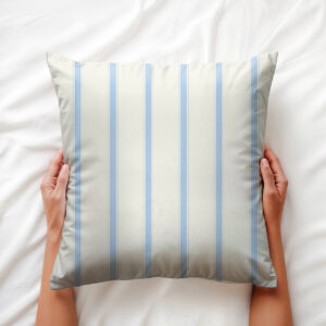 Ujęcie z góry: ręce trzymające poduszkę z delikatnymi błękitnymi paskami