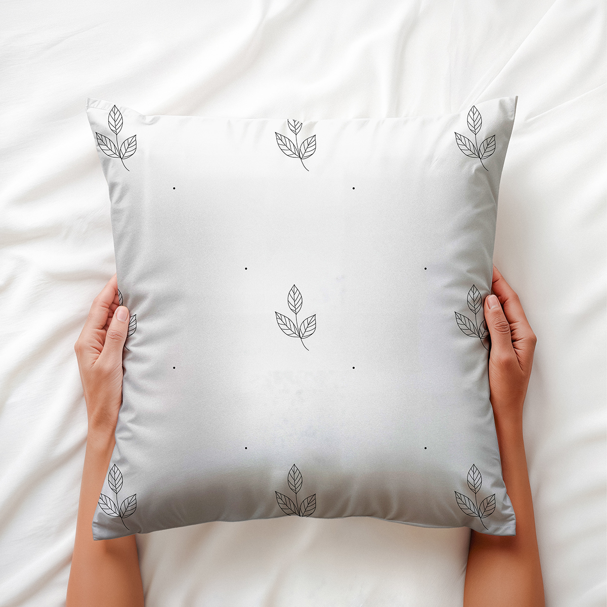 aranżacyjne ujęcie dłoni trzymającej miękką poduszkę z minimalistycznymi listkami