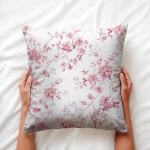 Widok poduszki trzymanej obiema dłońmi, detal różowego florystycznego wzoru