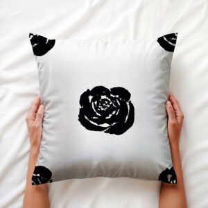 ręce trzymające poduszkę z wyraźnym motywem czarnej róży, ujęcie aranżacyjne
