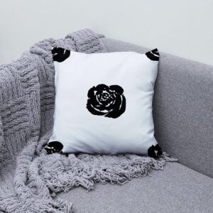 poduszka z motywem graficznej róży ułożona na kanapie obok pledu