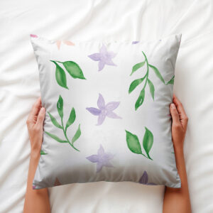 Widok z góry: dłoń trzyma poduszkę z motywem akwarelowych liści i kwiatów