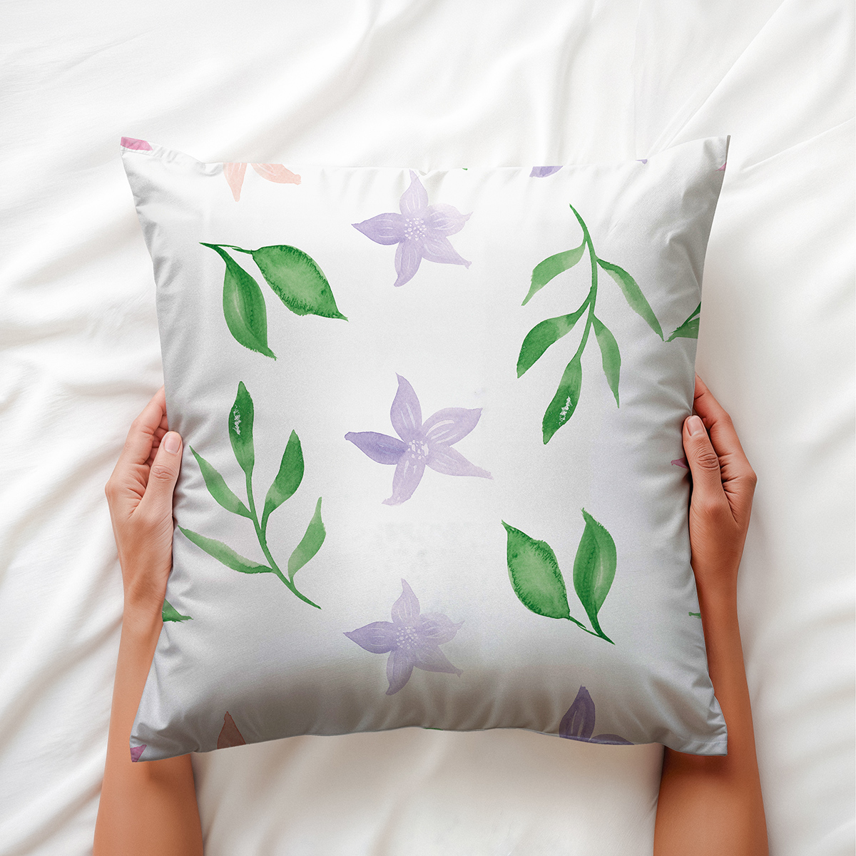 Widok z góry: dłoń trzyma poduszkę z motywem akwarelowych liści i kwiatów
