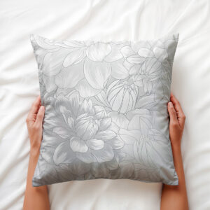 Ręce trzymają miękką poduszkę z delikatnym wzorem piwonii — detal i aranżacja na łóżku