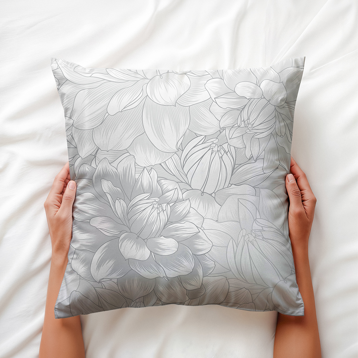 Ręce trzymają miękką poduszkę z delikatnym wzorem piwonii — detal i aranżacja na łóżku