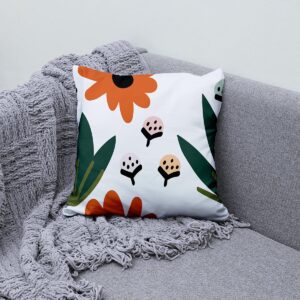 aranżacja na szarej kanapie pokazująca poduszkę ozdobną z folkowym motywem obok przytulnego pledu