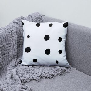 aranżacja poduszki z nieregularnymi grochami na szarej kanapie z plecionym kocem